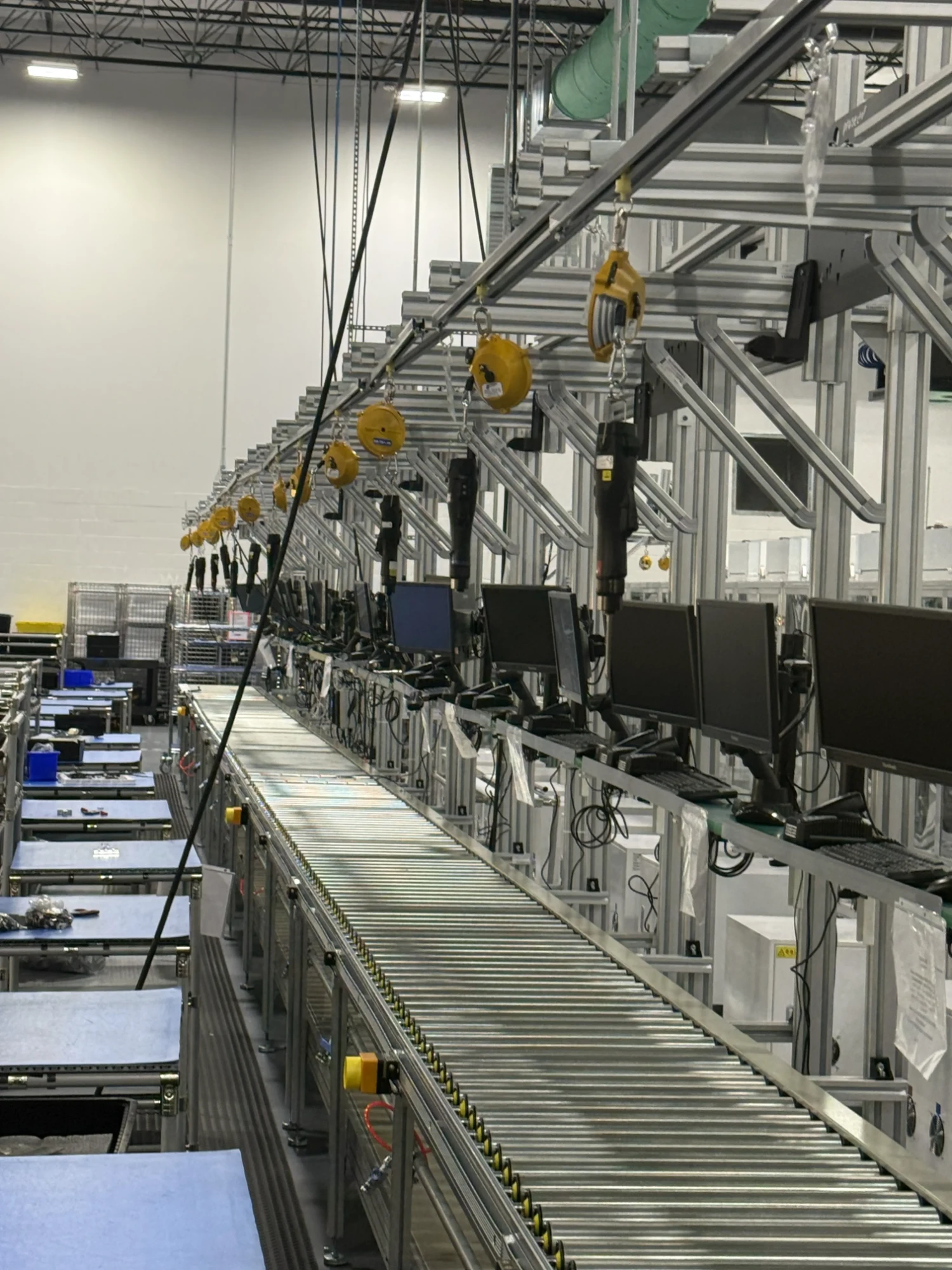 Long assembly line with yellow tool balancers and monitors