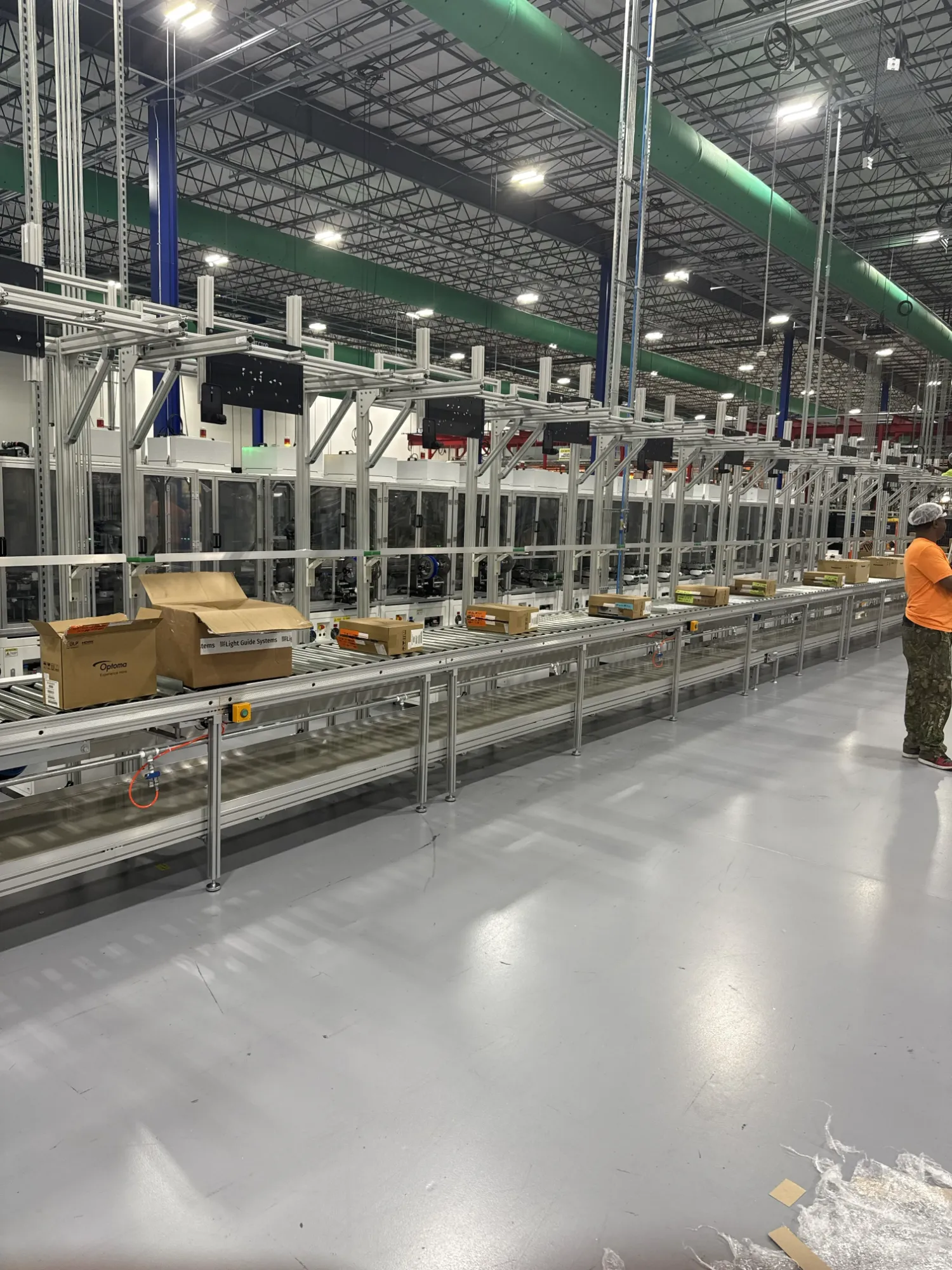 Roller conveyor with boxes alongside overhead frames